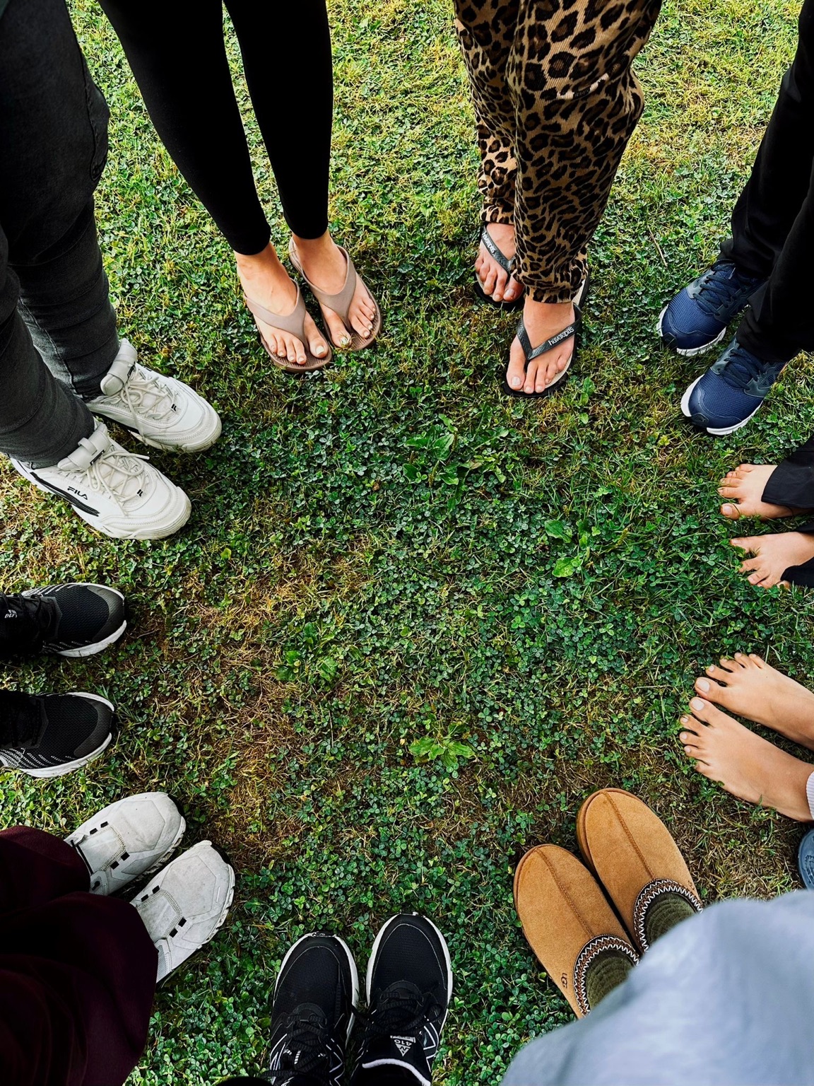 A circle of feet and hands on the grass