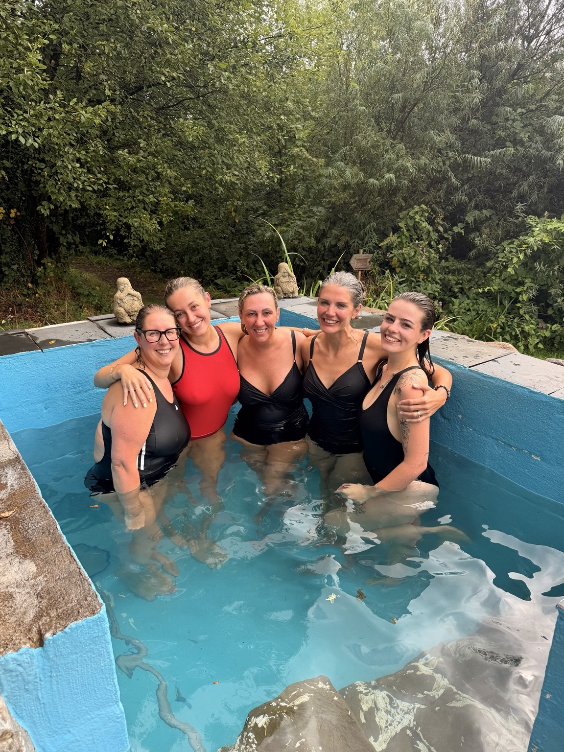 Five HELD retreat guests smiling together in the outdoor pool